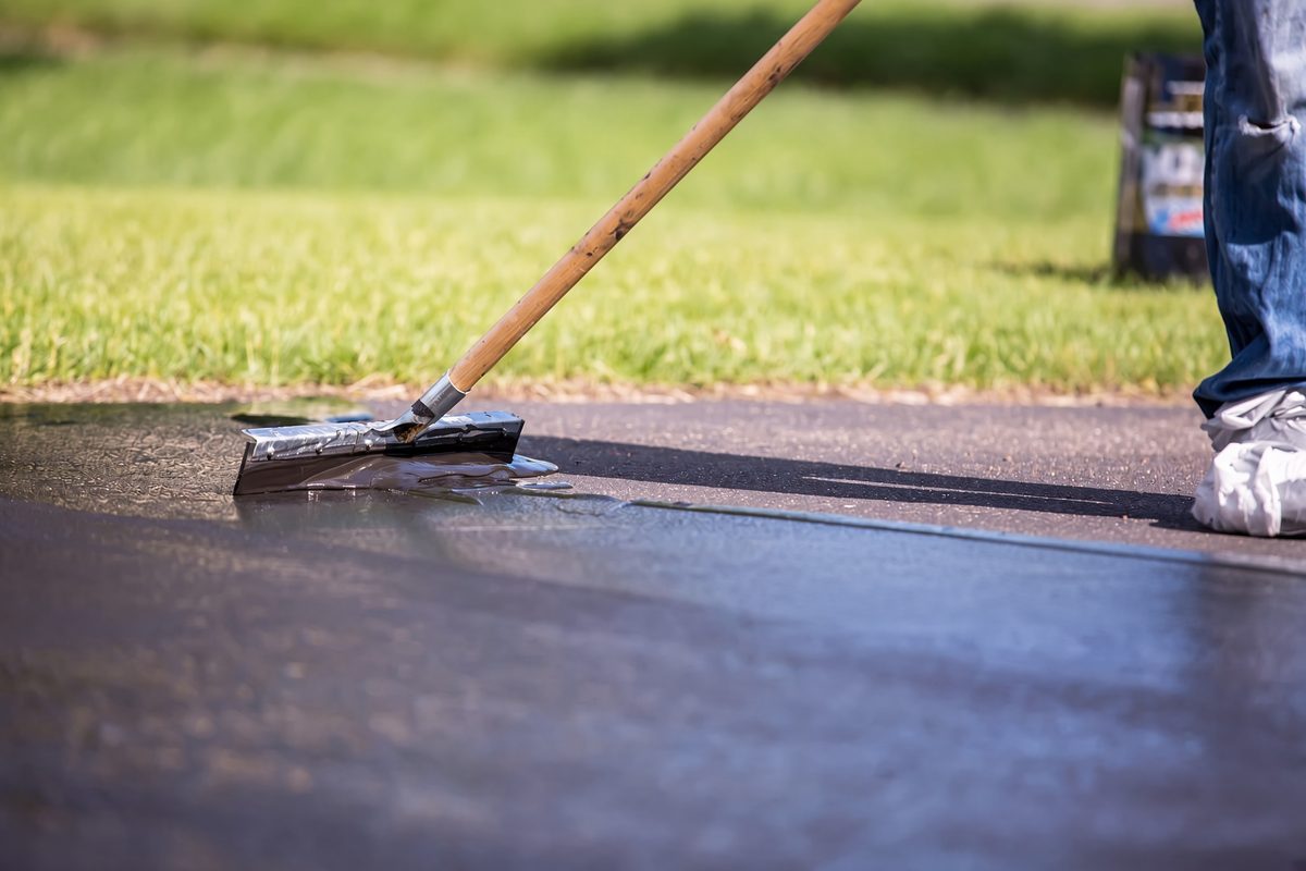 Applying commercial-grade driveway sealer by squeegee in Knoxville TN