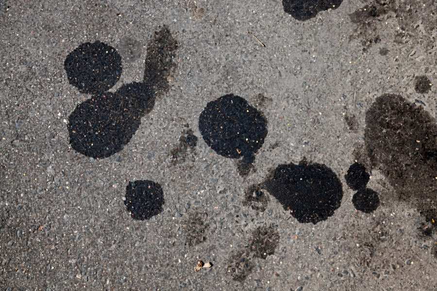 Priming oil spots on an asphalt driveway before sealer application in Knoxville